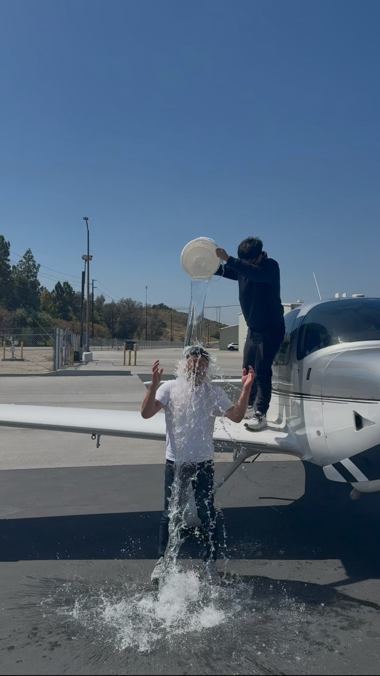 Water celebration beside a training aircraft after a first solo / 训练飞机旁的首次单飞泼水庆祝